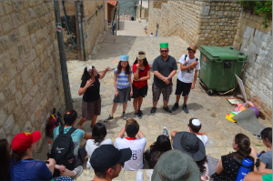 ALLEYS: Seniors listen to a guide during their tour of Tzfat May 26. They have sometimes gathered for informal davening outdoors.